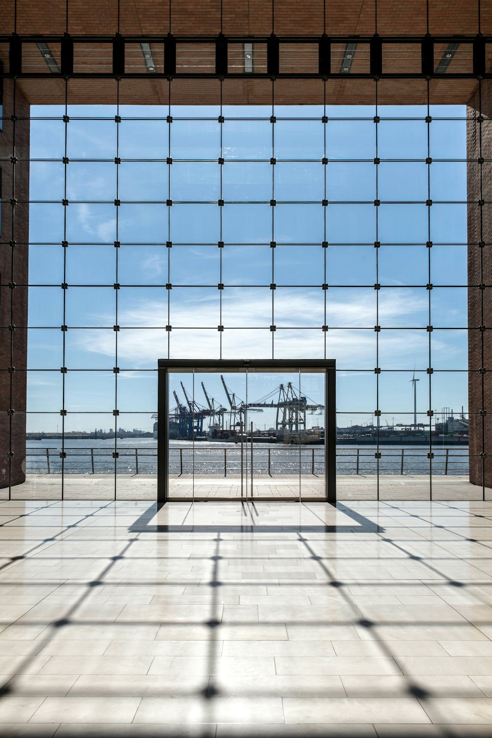Nowoczesne wnętrze budynku z dużymi oknami wychodzącymi na industrialny port.
