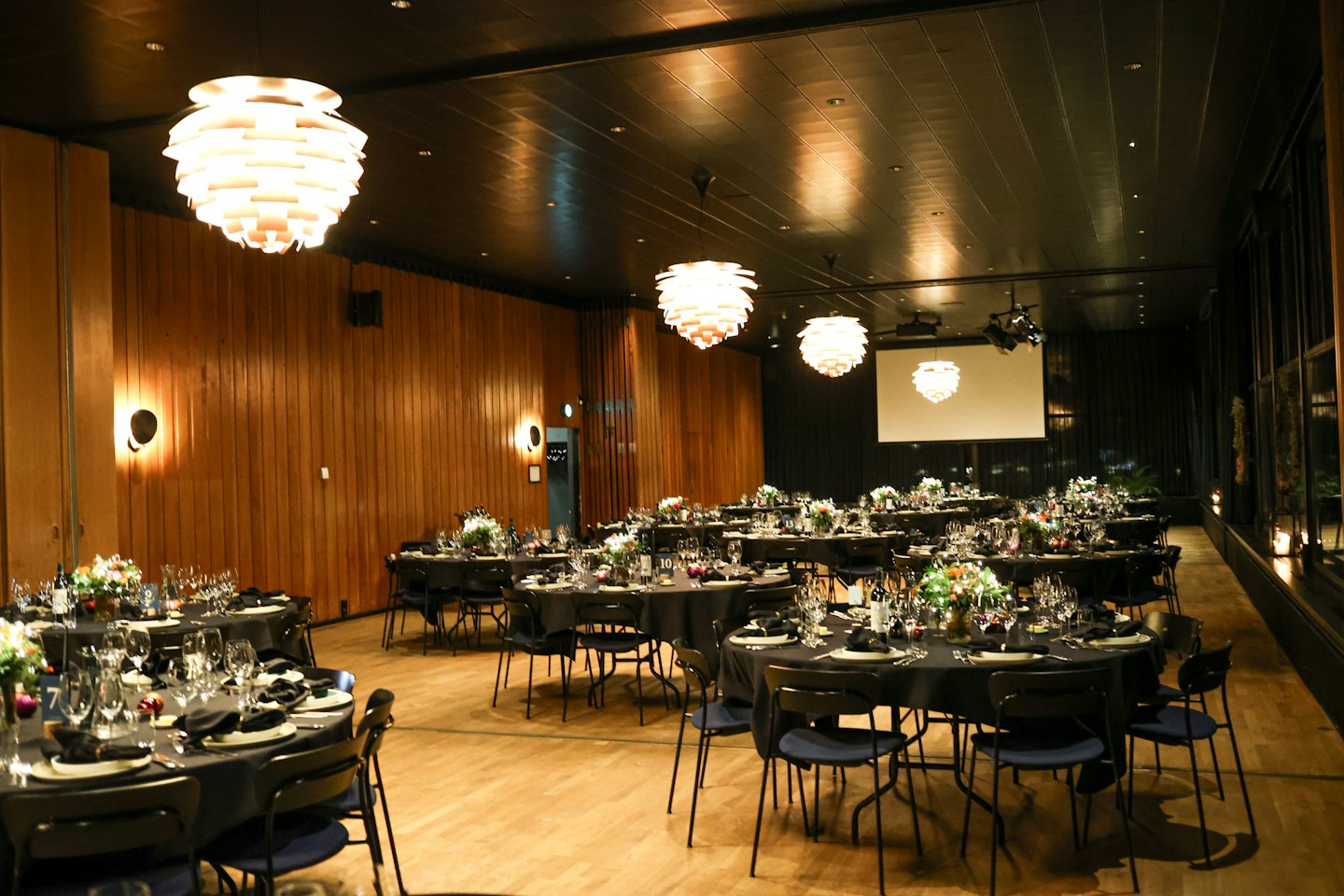 Elegancka sala bankietowa przygotowana z formalnymi stołami i kwiatowymi dekoracjami.
